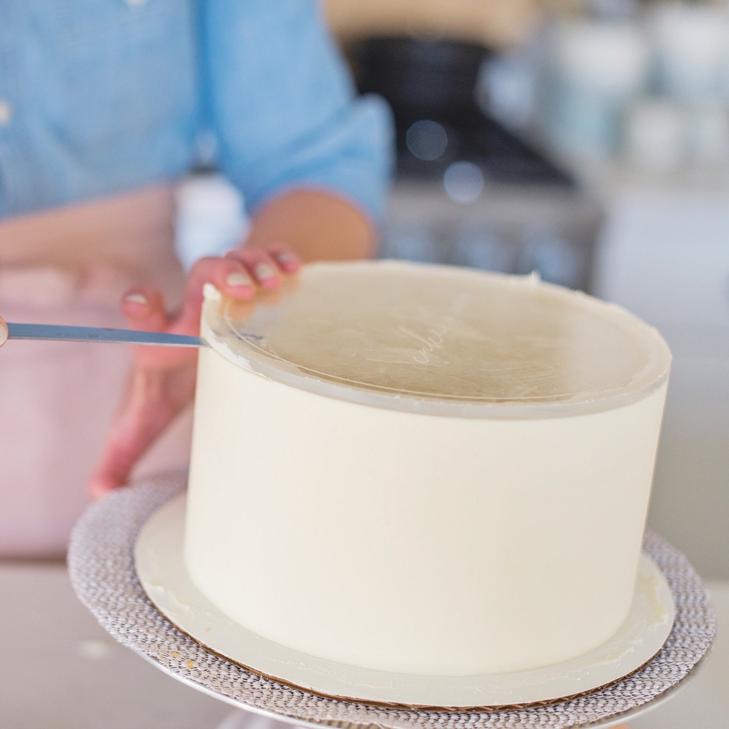 Close up of courtney taking off the acrylic disk after icing a white cake perfectly smooth