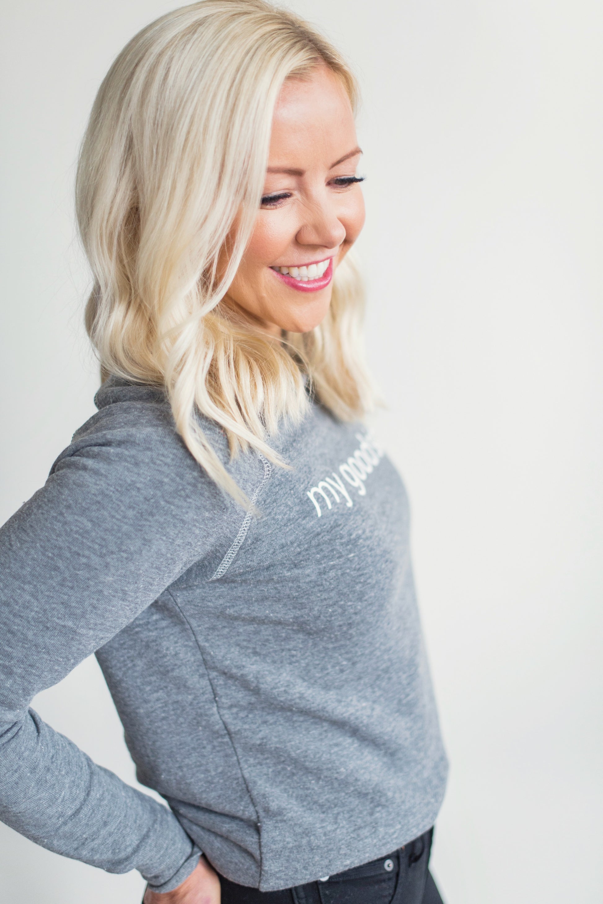 Side view of Courtney wearing her grey sweatshirt with the words 'my good side' that can be purchased on the website.