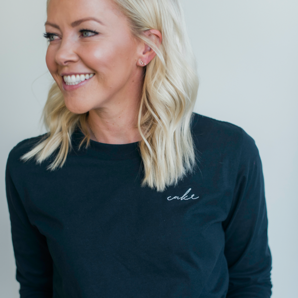 Close up of Courtney smiling and wearing her embroidered (white embroidery) black long sleeved 'Cake' shirt